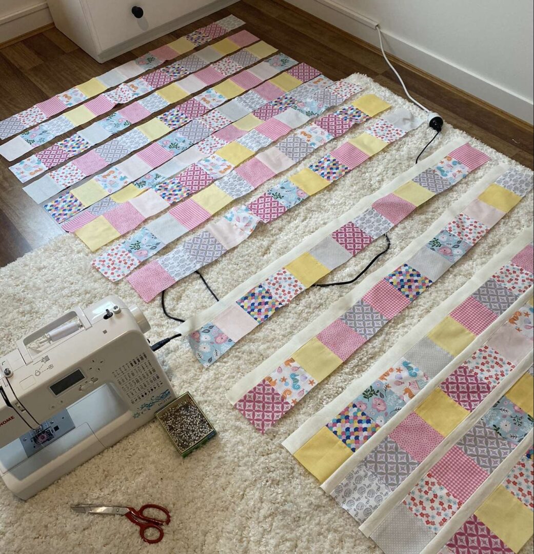 A room with unsown quilt patterns laying on the ground. There is a sowing machine next to the fabric. Image source: @littlelouise_designs